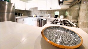Een moderne keuken met witte kasten, roestvrijstalen apparatuur en een groot eiland met een gegolven kom.