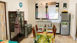 Une cuisine compacte comprenant un coin repas, un réfrigérateur, une cuisinière et un placard.
