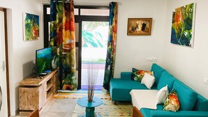 Un salon avec un canapé de couleur turquoise, un meuble TV en bois et des rideaux colorés.