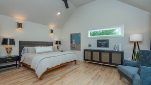 Una camera da letto con un letto, comodini, una ventola a soffitto, una finestra e una poltrona blu.