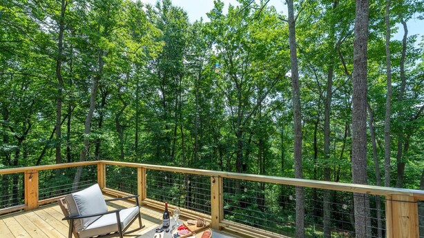 Un terrazzo in legno con tavolo, sedie e vista panoramica sulla foresta.