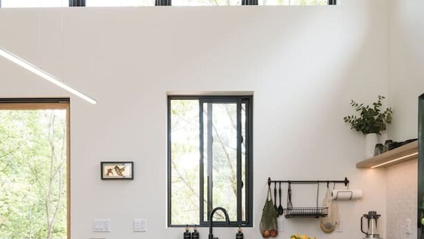 A modern kitchen with a wooden dining table, black chairs, and a black countertop. - Tiny Home in the Woods Hot Tub 4 Miles to DT Haus 50 (Asheville)