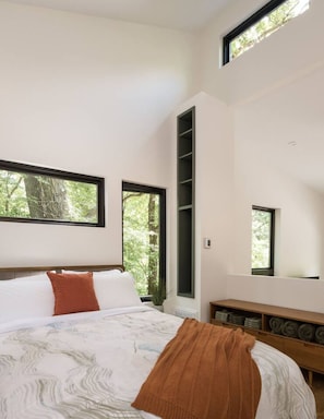 Relax in this serene bedroom with a large bed, wooden headboard, and shelving unit.