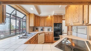 Una cocina moderna con armarios de madera, lavavajillas, estufa y un amplio ventanal con vistas al exterior.