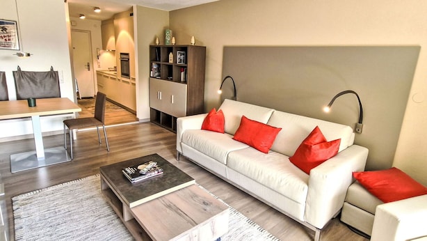 A modern living room with a white sofa, red cushions, a wooden coffee table, and a dark rug. - Lovely apartment for 2 guests with WIFI, TV and balcony (Seefeld In Tirol)