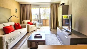 A modern living room with a sofa, coffee table, and TV. There is a sliding glass door leading to an outdoor area. - Lovely apartment for 2 guests with WIFI, TV and balcony (Seefeld In Tirol)