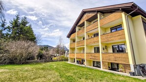 A multi-story hotel with a flat roof, balconies, and a grassy courtyard. - Lovely apartment for 2 guests with WIFI, TV and balcony (Seefeld In Tirol)