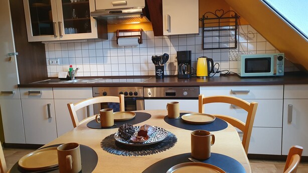 Een moderne keuken met witte kastjes, een roestvrijstalen fornuis en een magnetron.