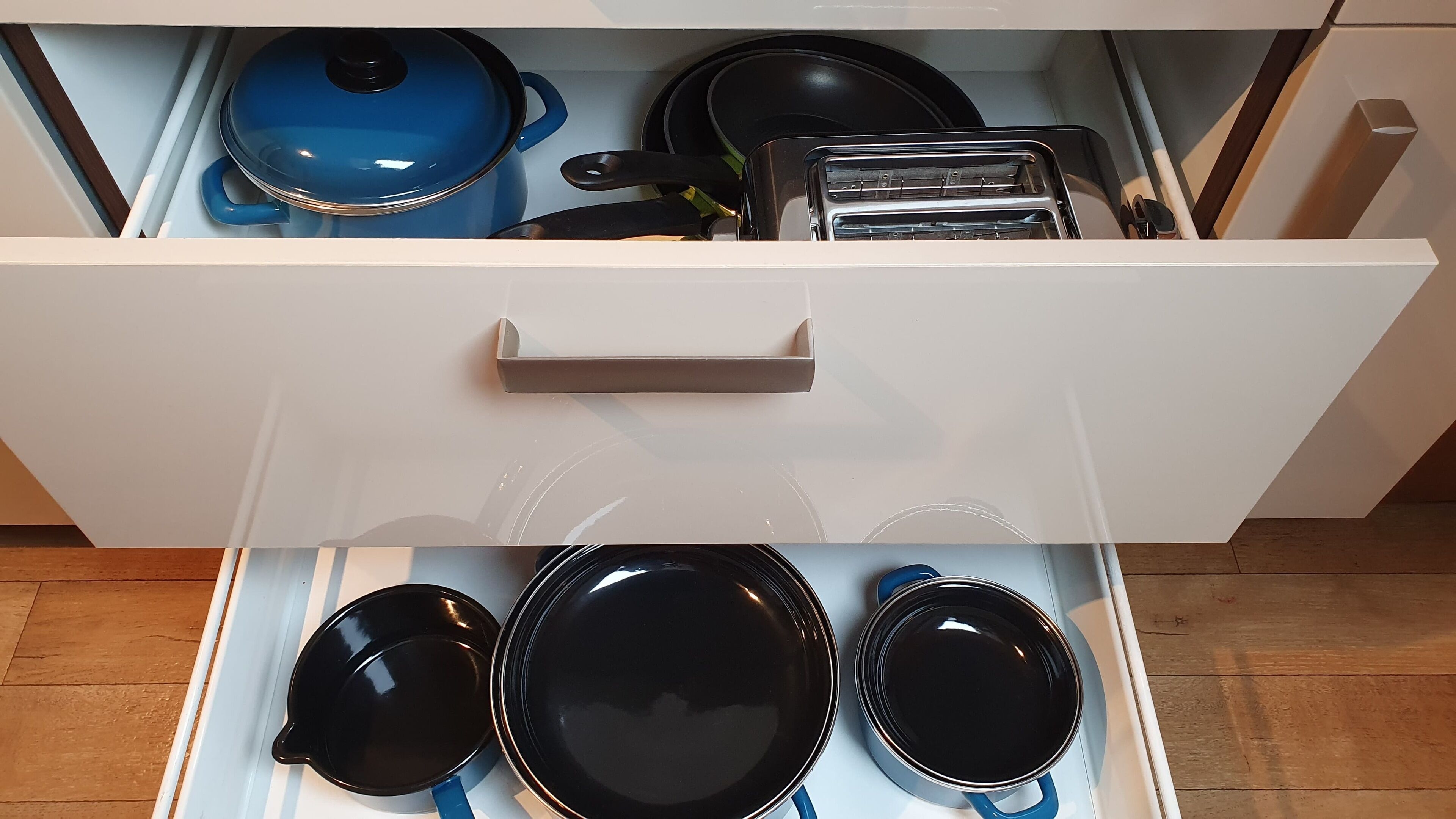 Een keukula open met verschillende kookgerei, zoals pannen, braadpannen en een broodrooster.