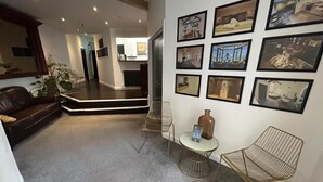 A living room with a brown leather sofa, a coffee table, and a wall with framed pictures.