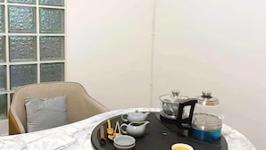 Une table à manger sur laquelle se trouve un plateau noir, avec une théière, des tasses et une machine à café.