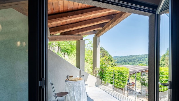 A balcony with a table and chairs, a view of a mountainous landscape, and a wooden ceiling structure. - Wonderful private villa for 6 people with private pool, WIFI, TV, patio and pets allowed (Bossolasco)