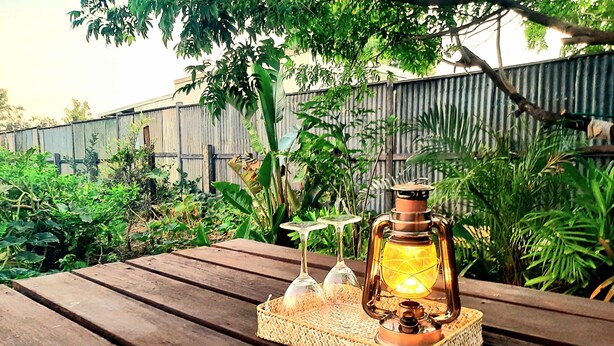 A wooden table with a woven tray holding a lantern, two wine glasses, and a bottle. - Oakwood House at Wild Wood Park Retreat | 5-Bedroom home for Families & Groups (Tambo)