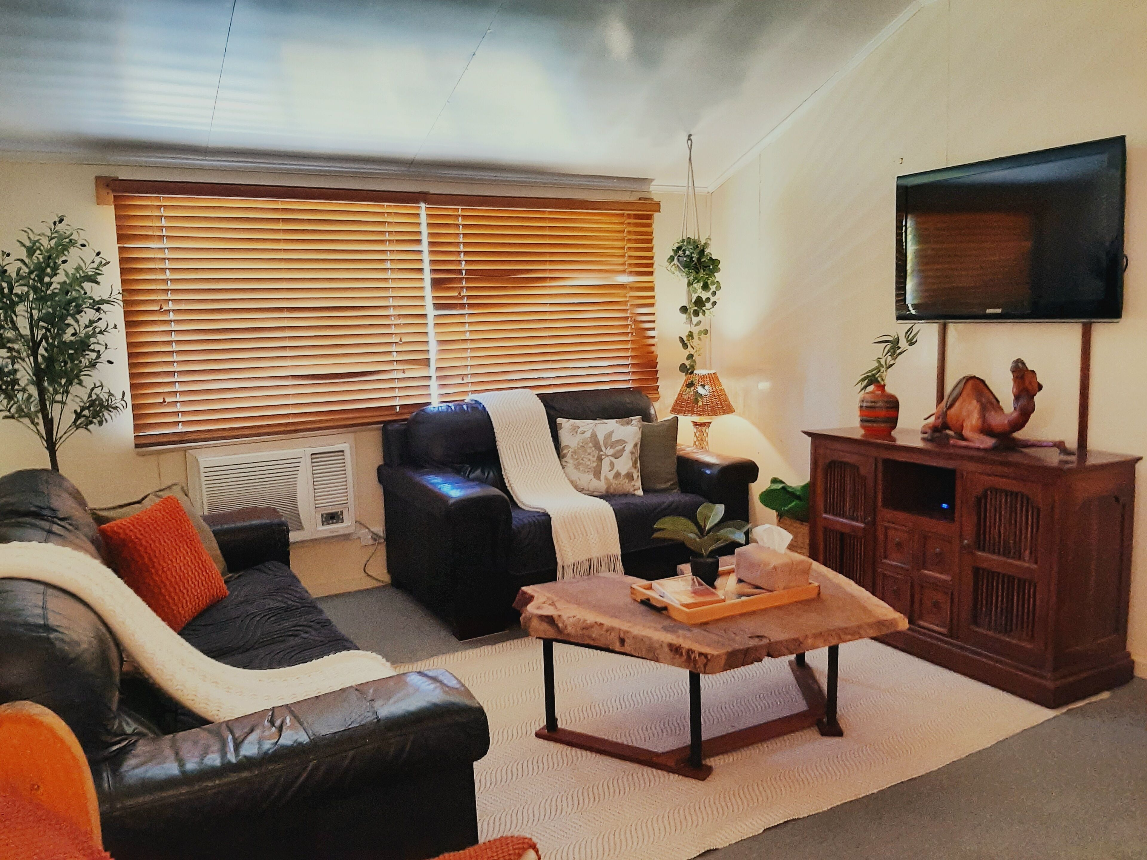 A living room with a leather sofa, a wooden coffee table, and a television on a wooden cabinet.