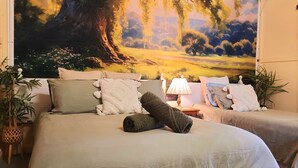 A bedroom with a large bed, two bedside tables, a lamp, and a large landscape painting on the wall. - Oakwood House at Wild Wood Park Retreat | 5-Bedroom home for Families & Groups (Tambo)