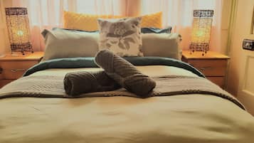 Una cama bien hecha con una colcha, almohadas y un par de calcetines doblados.