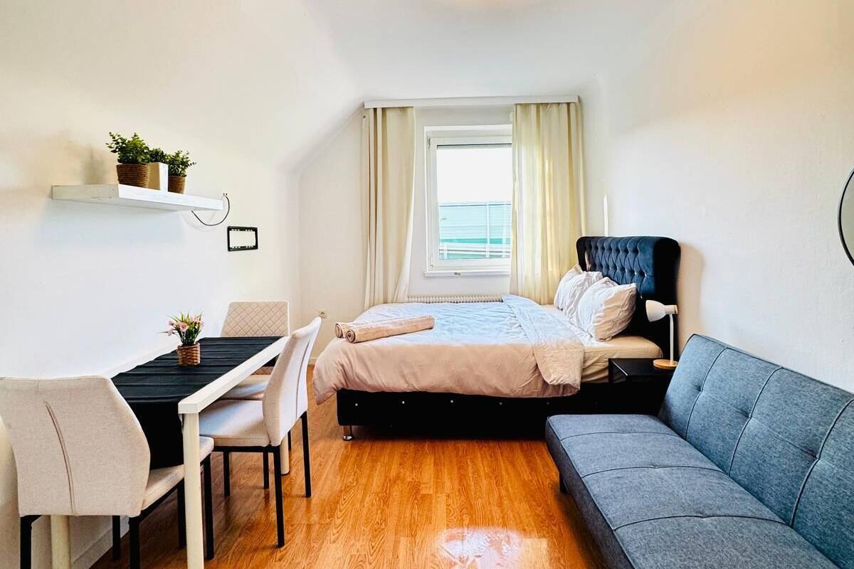A compact bedroom with a bed, a sofa, a desk, and a chair.