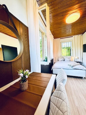 A cozy bedroom with a bed, a bedside table with a vase of flowers, and a large mirror. - Cozy Garden Villa near Danube For 16P (Vienna)