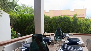 A dining table set outdoors with plates, glasses, and a green vase. - Villa le palme, 500 mt from the beaches of Sas Linnas Siccas Bay. (Orosei)
