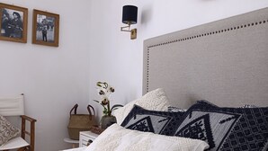 A neatly arranged bedroom with a bed, pillows, a wall-mounted lamp, and framed pictures. - Villa le palme, 500 mt from the beaches of Sas Linnas Siccas Bay. (Orosei)