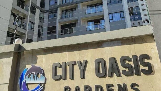 Ein Hochhaus mit einem Schild, auf dem 'City Oasis Gardens' steht.