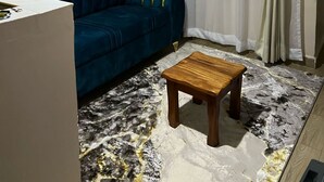 En stue med en blå sofa, et træbord og et vindue med lette gardiner.