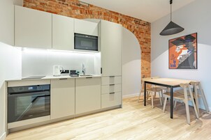 Una cocina moderna con electrodomésticos integrados, un comedor con mesa y sillas, y una pared de ladrillo.