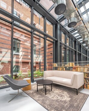 Un interior moderno con ventanas amplias, un sofá, una silla y una mesa de centro.