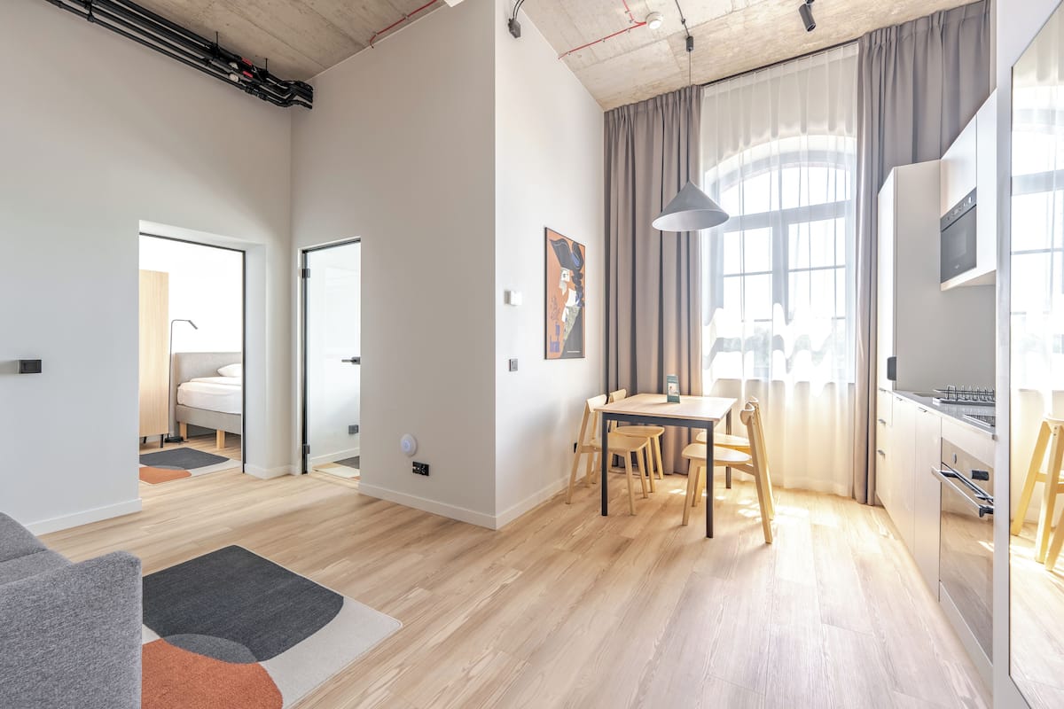 Un appartement moderne comprenant un coin repas, une cuisine et une chambre à coucher visible à travers une porte ouverte.