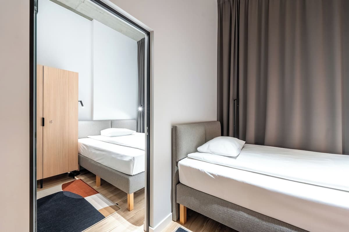 Une chambre à coucher moderne avec un placard à portes miroir, un lit simple et une petite table de chevet.