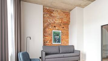 Ein modernes Wohnzimmer mit einer Ziegelwand, zwei grauen Sofas und einem Holzboden.