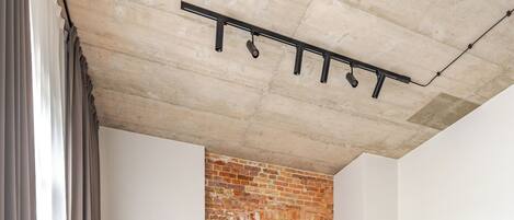 A modern living room with a brick wall, two grey sofas, and a wooden floor.