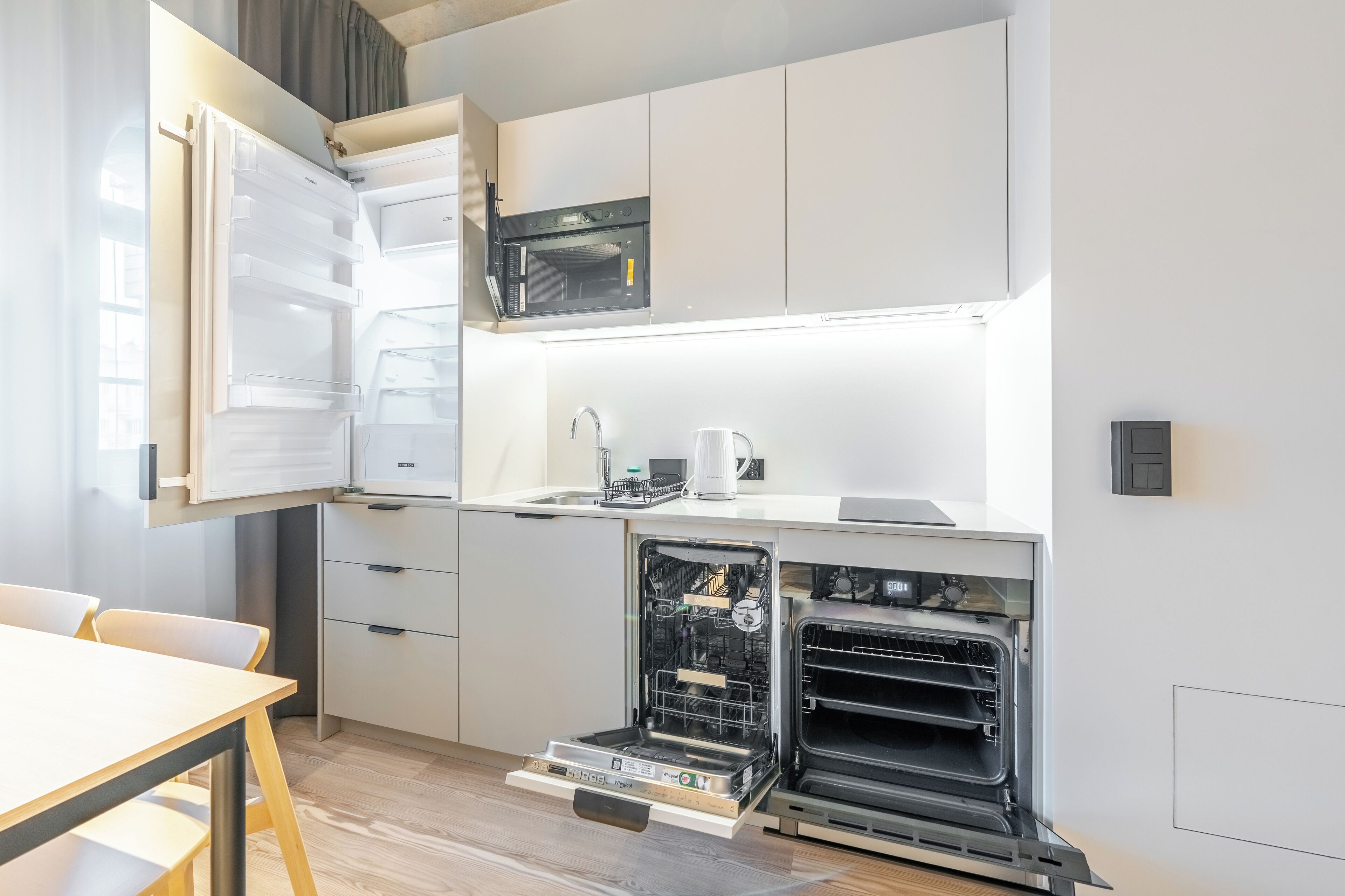 Una cocina compacta con horno empotrado, microondas y lavavajillas.