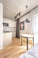 A modern kitchen with a central island, wooden flooring, and a dining area with a table and chairs.