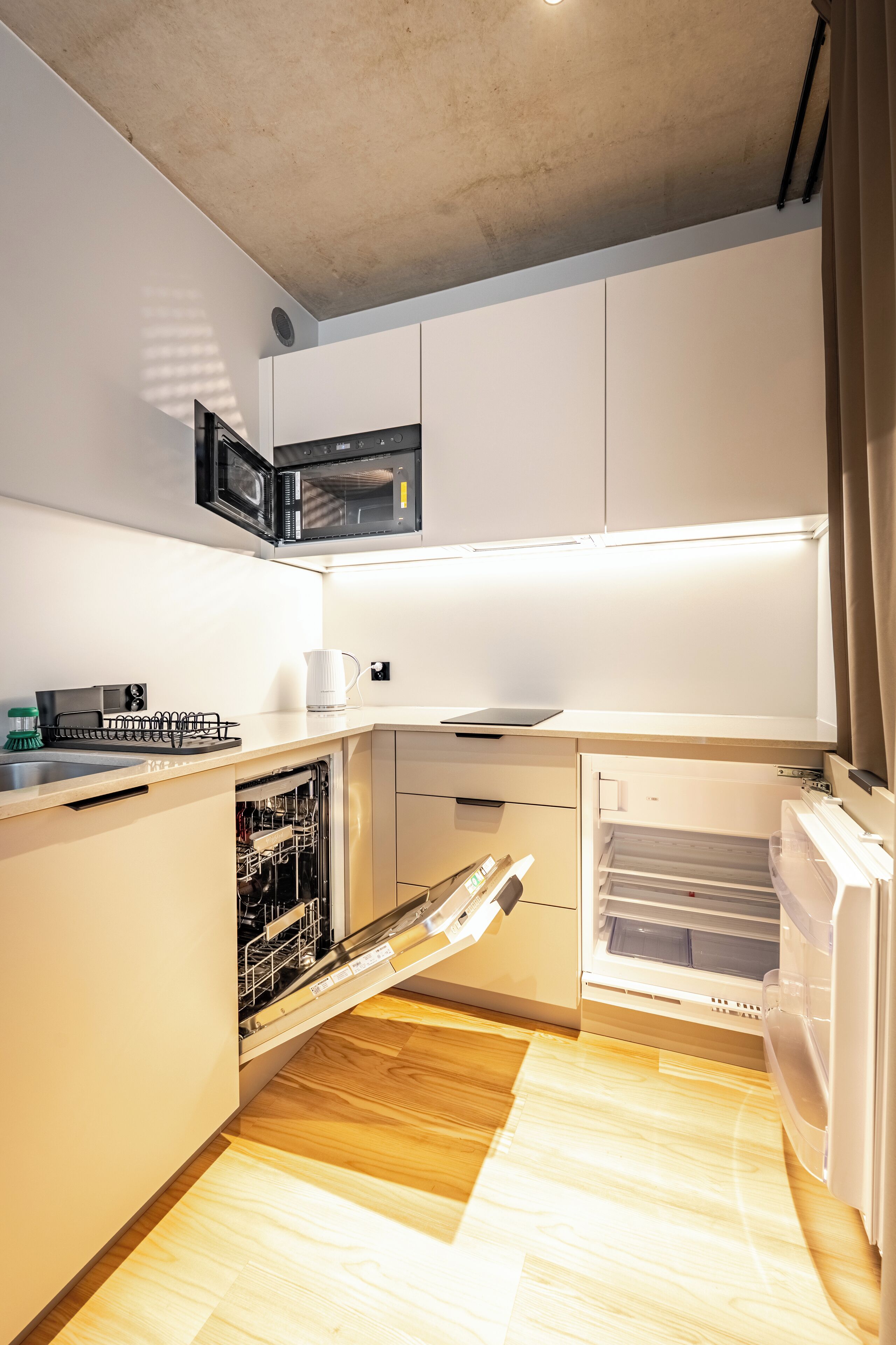 A compact kitchen with a microwave, dishwasher, and refrigerator.