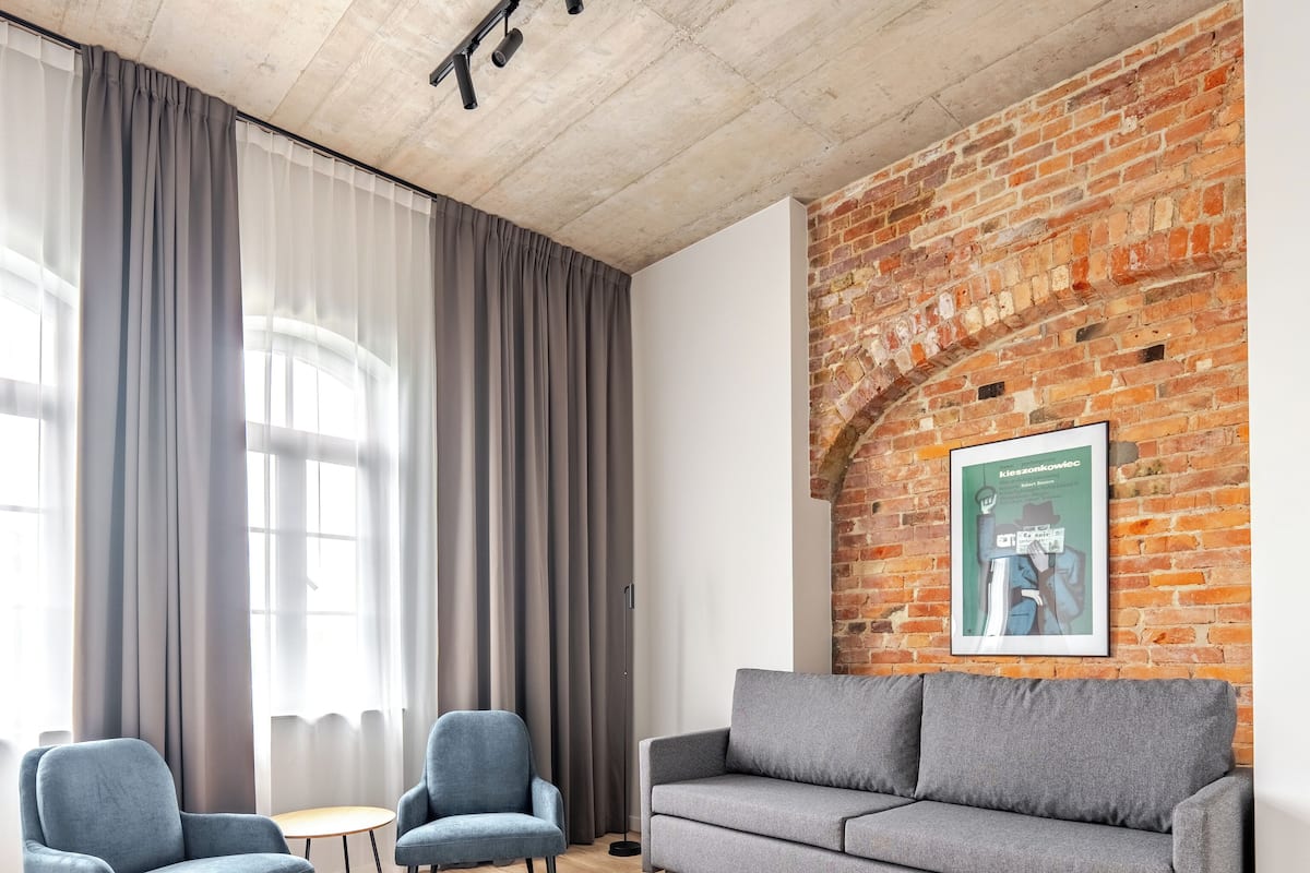 Un salon moderne avec un mur en briques, deux canapés gris et une table ronde.