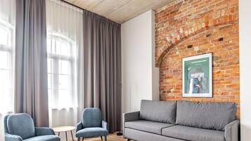 Una sala moderna con pared de ladrillo, dos sofás grises y una mesa redonda.