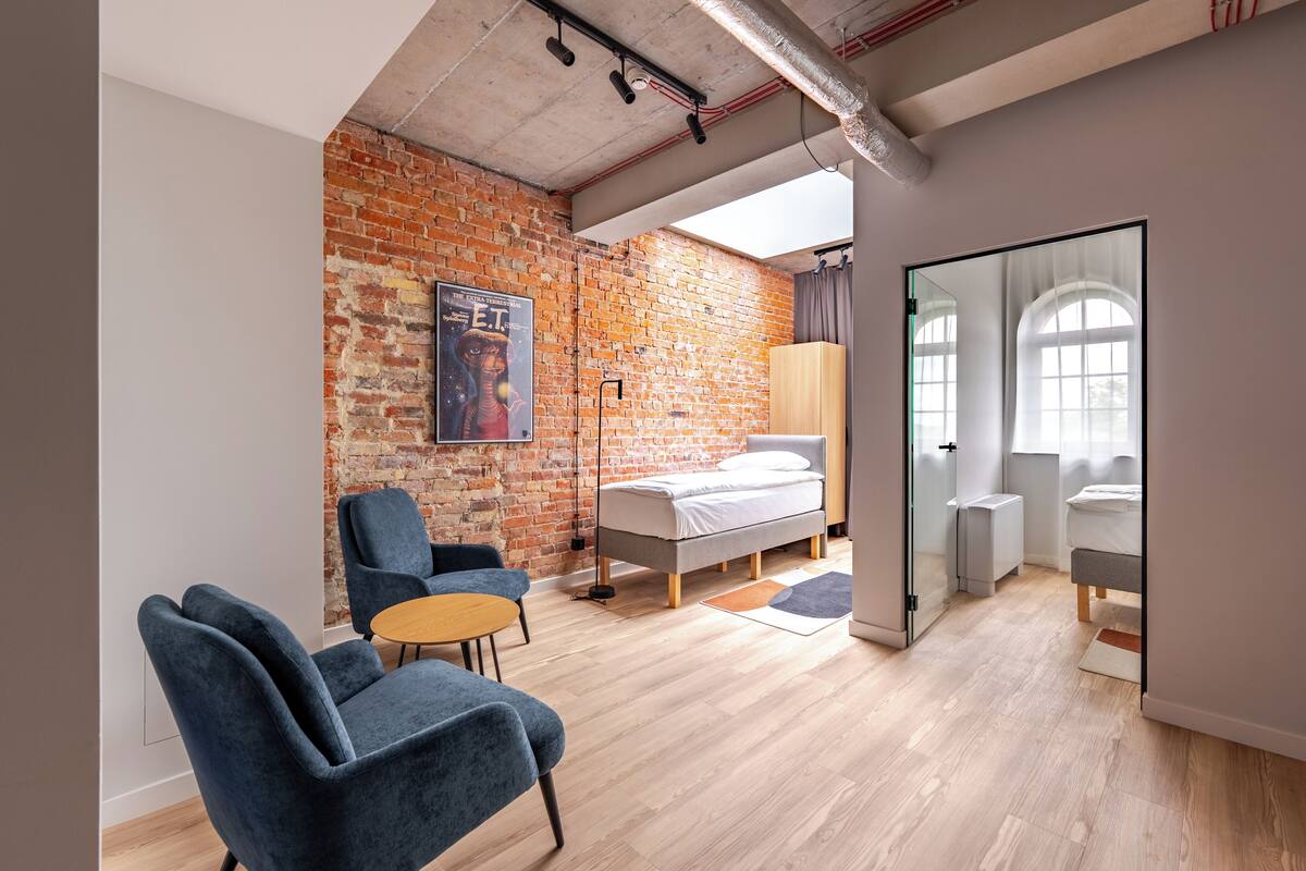 Une chambre moderne avec un mur en briques, un lit, un bureau et une chaise.