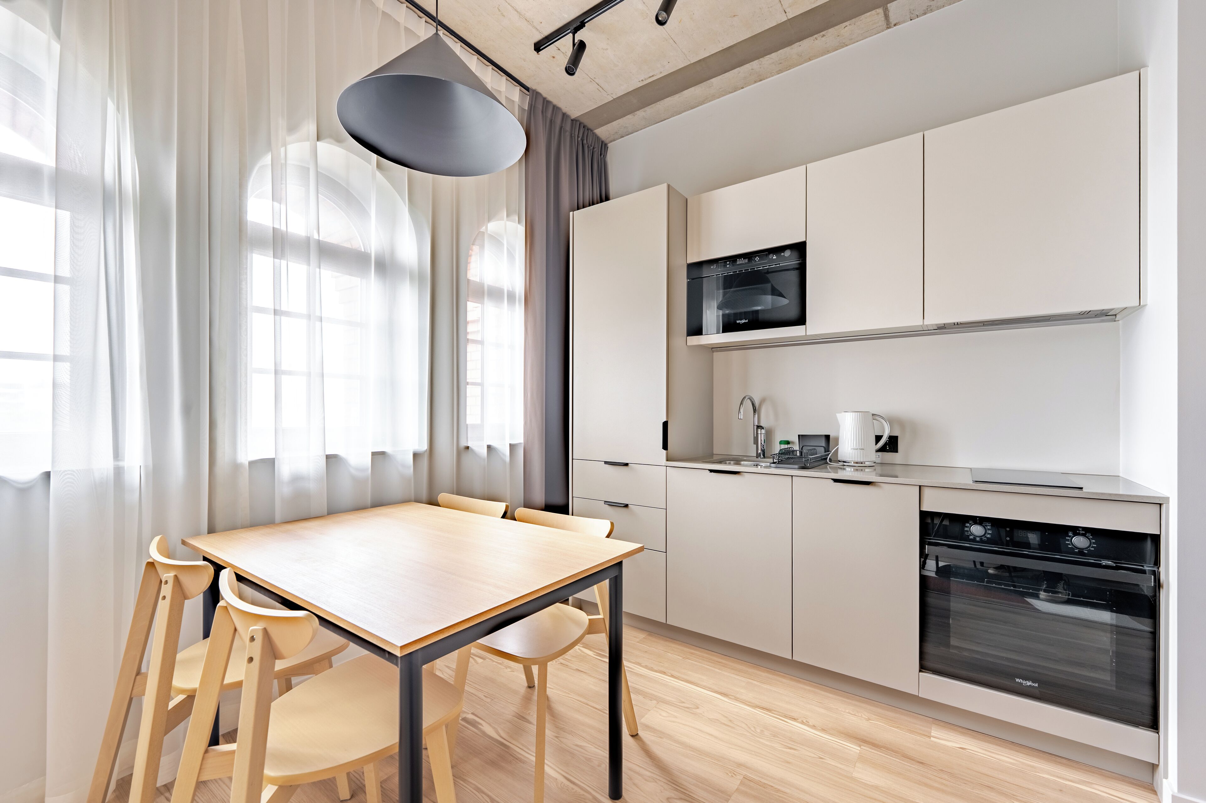 A modern kitchen with a dining table and chairs, a built-in oven, and a microwave.