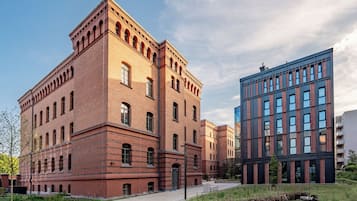 Un edificio grande de ladrillo con varias ventanas y un edificio moderno de vidrio contiguo.