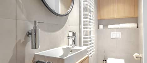 Une salle de bain moderne avec un grand miroir, un lavabo et des toilettes.