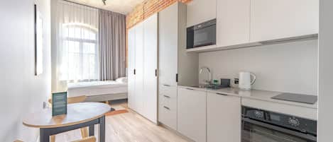 Een moderne keuken met witte kasten, een magnetron, een koffiezetapparaat en een eethoek met een tafel en stoelen.