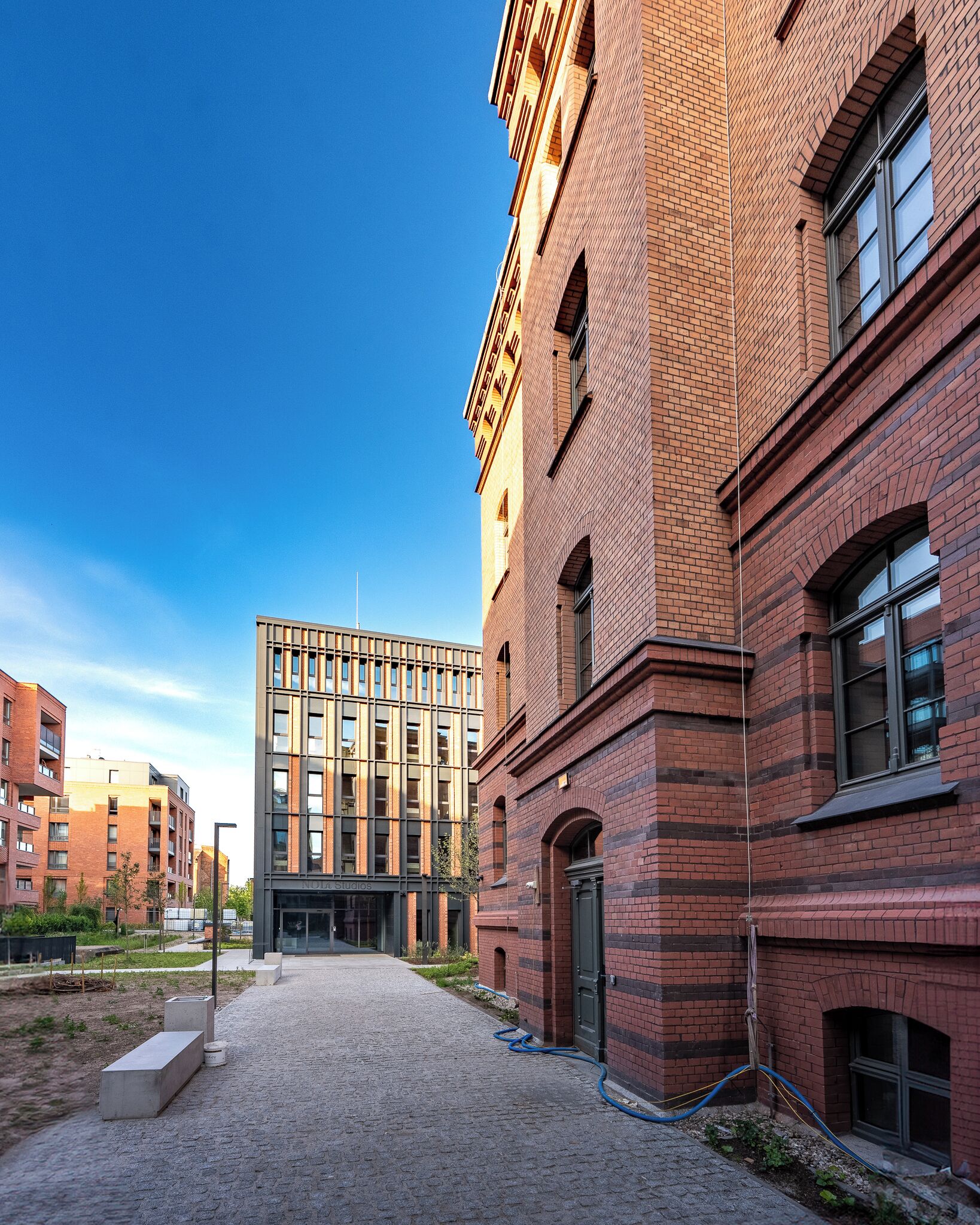 Un patio con un edificio moderno, fachada de ladrillo y ventanas amplias.
