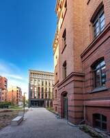 En gårdsplads med en moderne bygning, med murstensfacade og store vinduer.