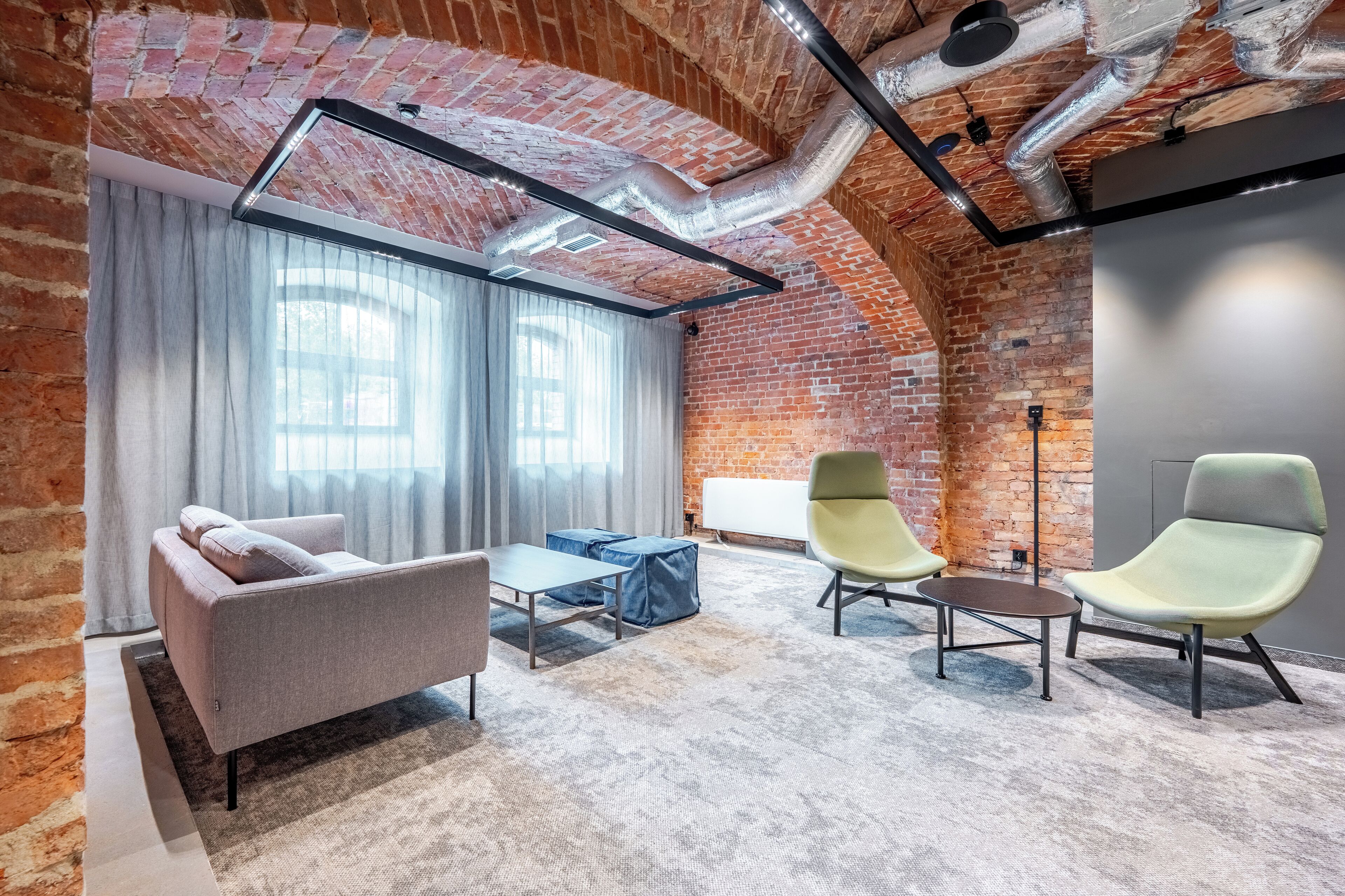 Un espacio de oficina moderno con paredes de ladrillo visto, techo estilo loft y una mezcla de mobiliario contemporáneo y clásico.