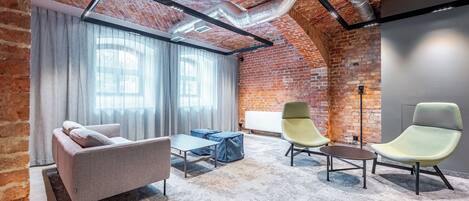 Un espacio de oficina moderno con paredes de ladrillo visto, techo estilo loft y una mezcla de mobiliario contemporáneo y clásico.