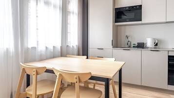 Una cocina moderna con armarios blancos, un microondas negro y una mesa de comedor de madera con sillas.
