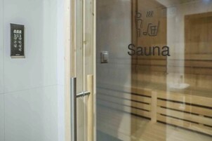 A glass door with a sauna sign and a digital keypad on the wall.