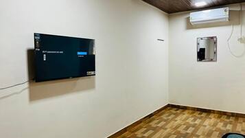 A room with a flat-screen TV mounted on the wall, a ceiling fan, and a small mirror.