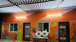 Une pièce aux murs orange, avec deux fenêtres, une porte et une table sur laquelle se trouvent deux bouées gonflables et une bouteille.
